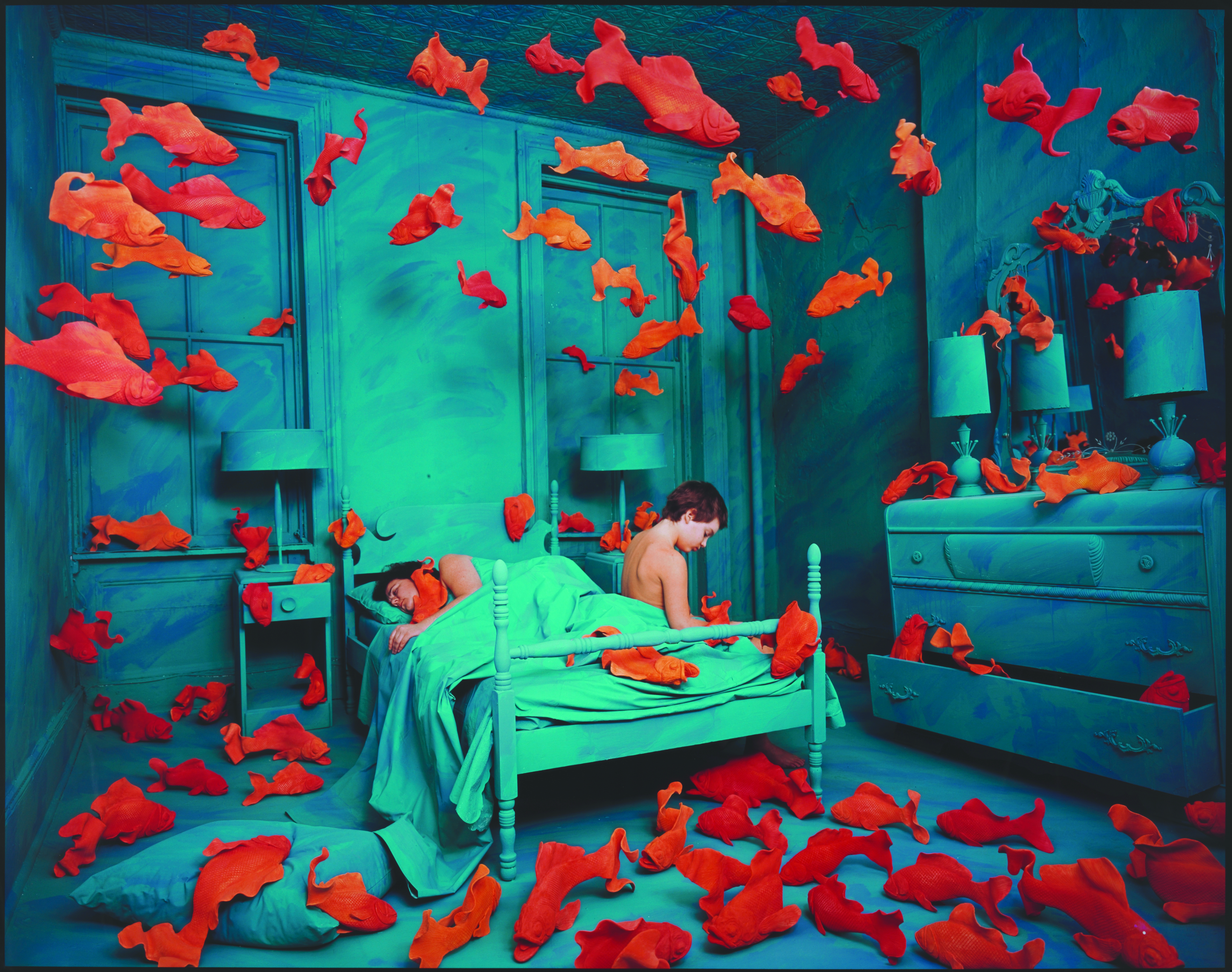 woman sitting on bed surrounded by floating fish