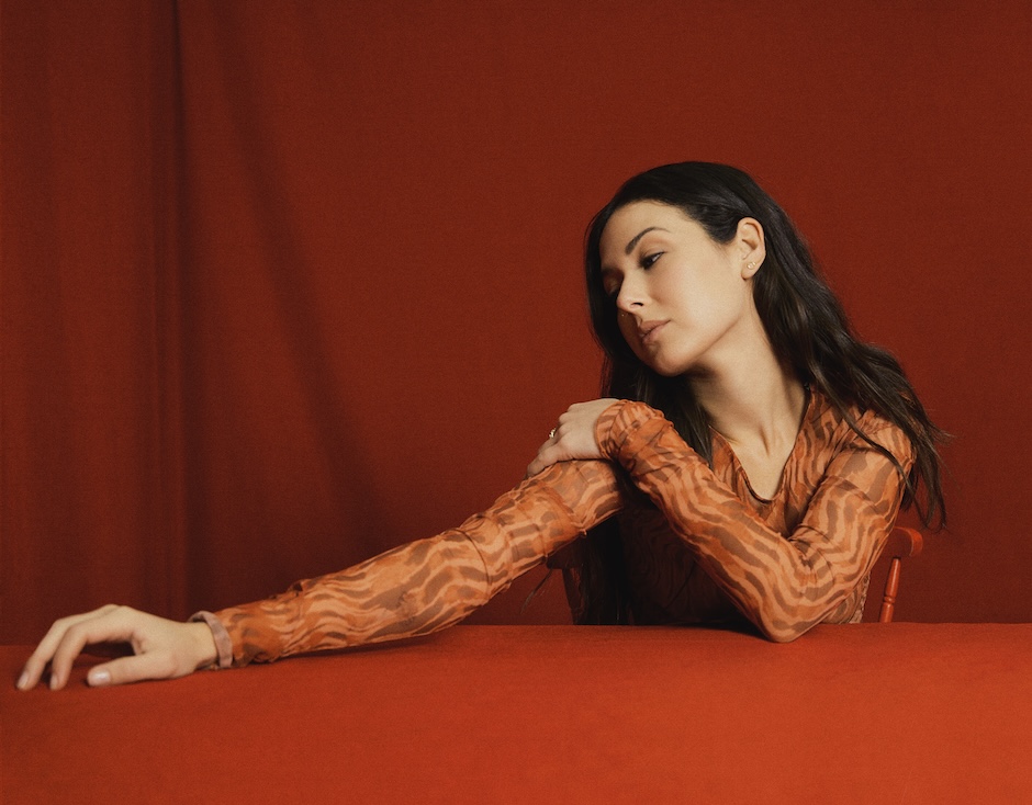 nella sitting at a red-covered table with a red background