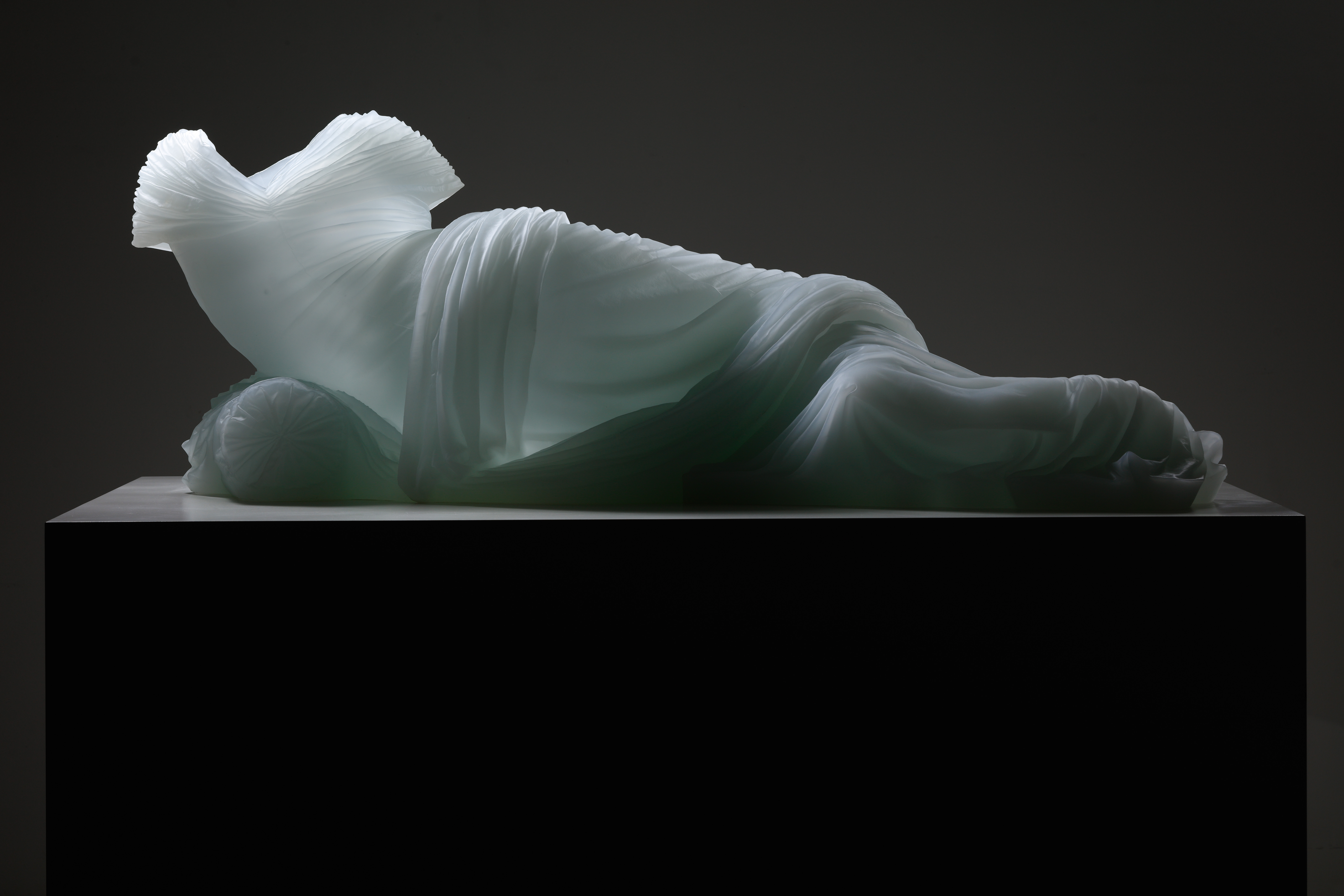 Form of woman laying, just glass dress providing form
