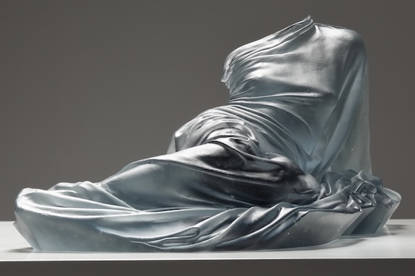Form of woman laying, just glass dress providing form