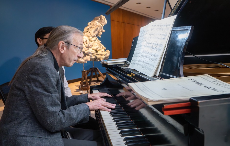 man playing piano in art gallery by Karen LaMonte sculptures against a blue wall